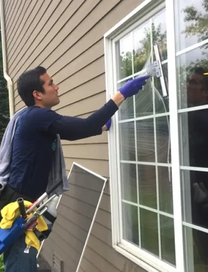 Technician cleaning windows on a house
